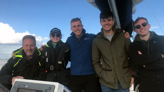 Group of sailing school students smiling together on deck during training