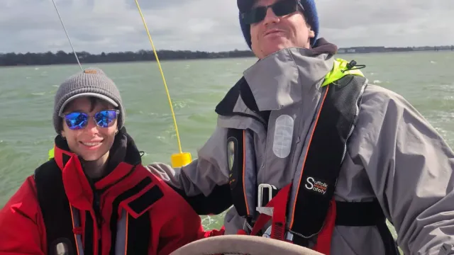 Sailing school students sharing the helm of a yacht on a sunny day