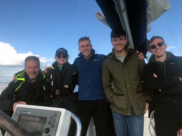 Group of sailing school students smiling together on deck during training
