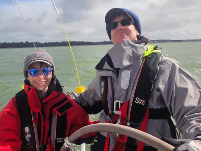 Sailing school students sharing the helm of a yacht on a sunny day