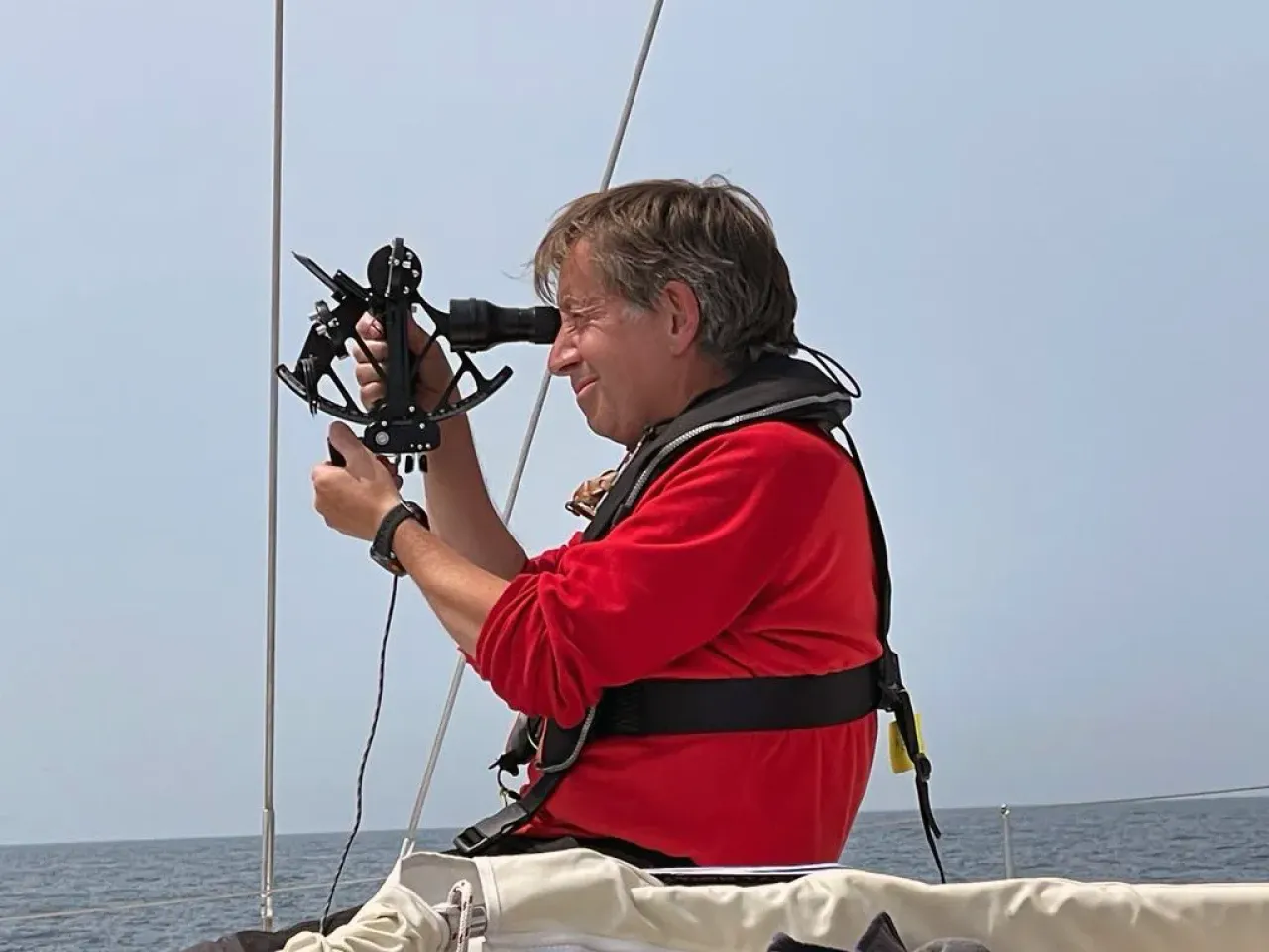 Sailing school student using a sextant for celestial navigation at sea