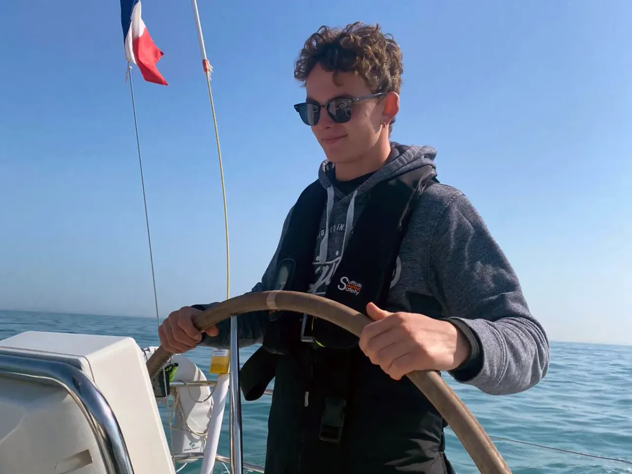 Sailing school student steering a yacht in calm weather