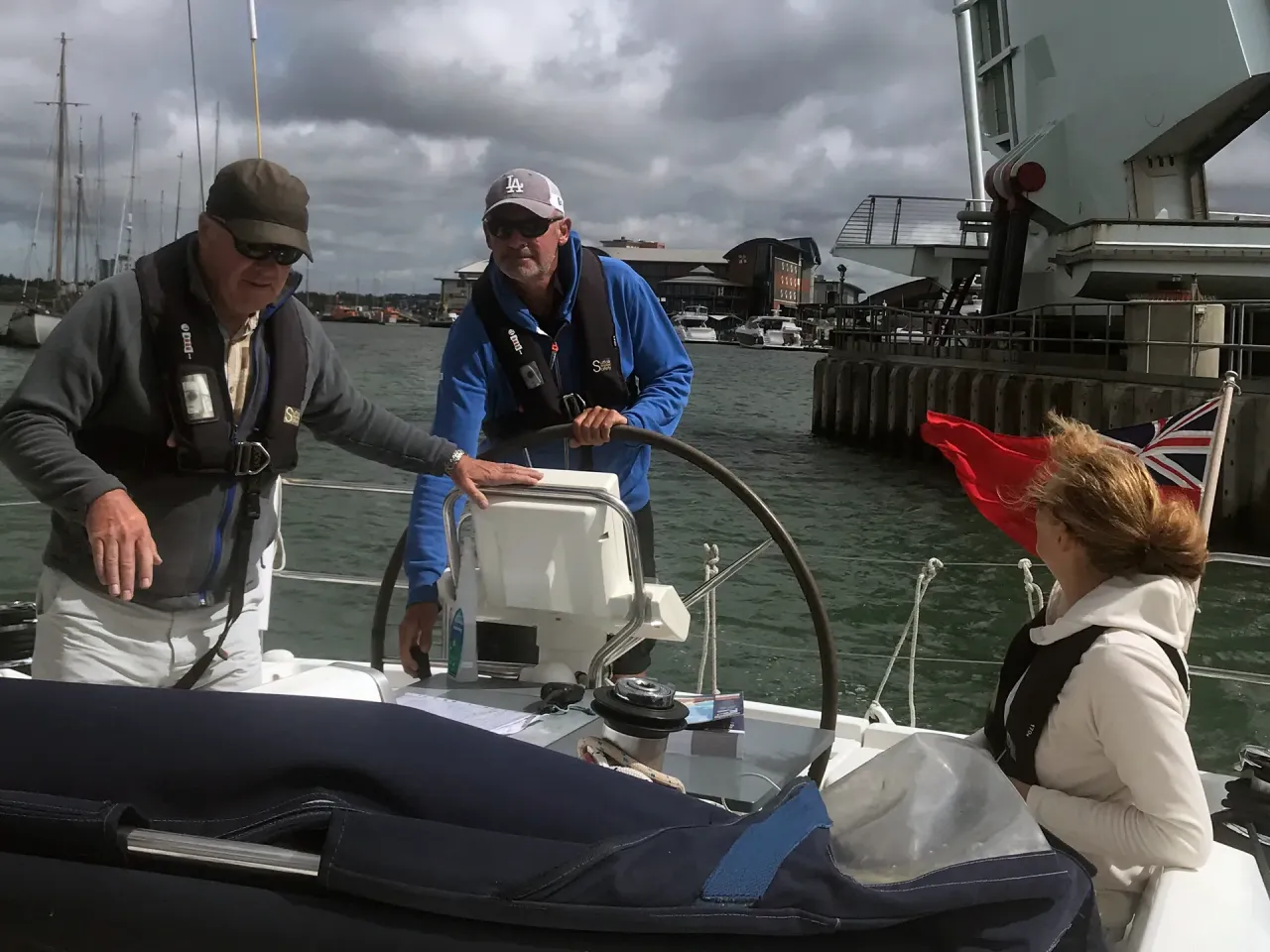 Sailing school instructor guiding students at the helm while leaving the marina